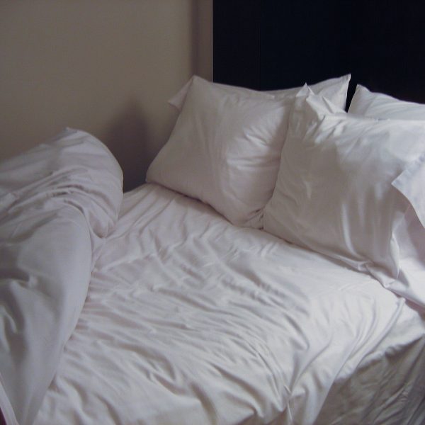 A bed with a clean white duvet and pillows